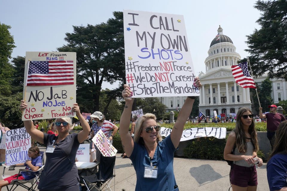 Jenean Lubinski, who works as a patient registration representative at Marshall Medical Center in Placerville, center, joins others in a demonstration against mandatory vaccinations at the Capitol in Sacramento, Calif., Monday, Aug. 16, 2021. California is mandating COVID-19 vaccinations for all health care workers and will require state government and school staff to be vaccinated or regularly tested. (AP Photo/Rich Pedroncelli)