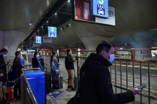 People wait for scarce taxis after arriving at the nearly-deserted Wuhan train station