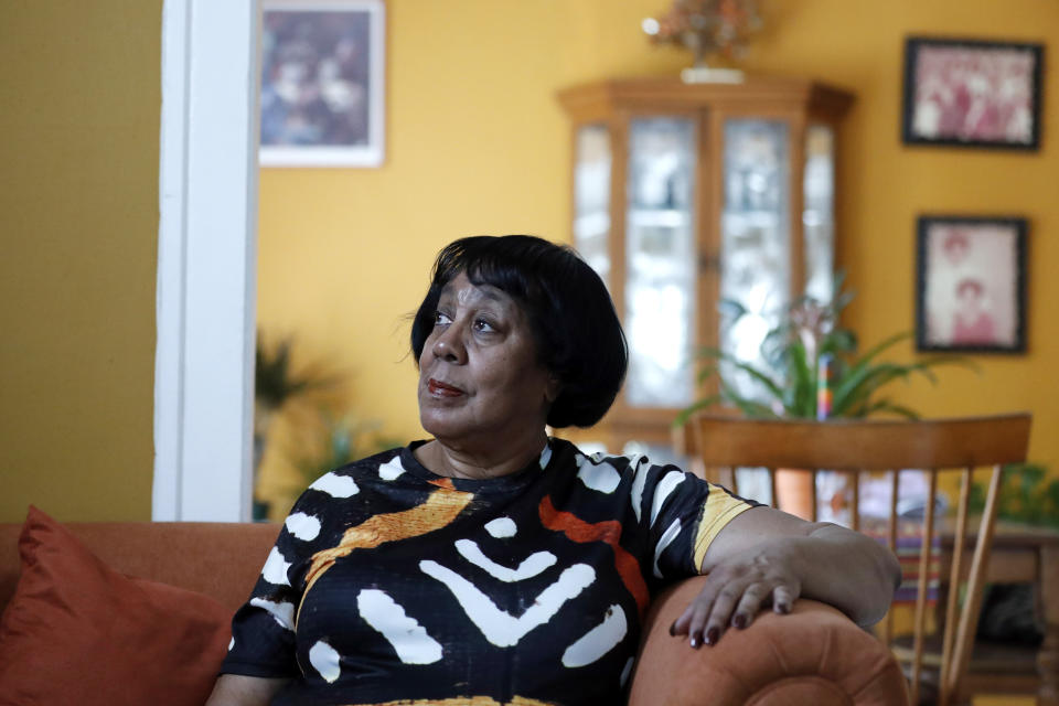 Jo-Ann Cromer seated on her couch, with photos of her family on the walls in the background.