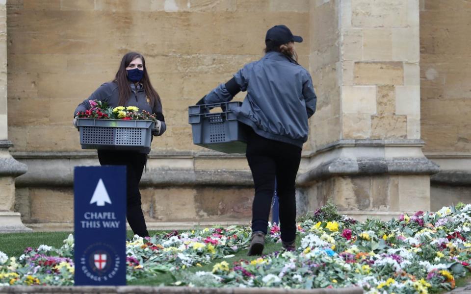 Staff place flowers on the ground outside St George's Chapel which were left by well-wishers outside Windsor Castle, Berkshire - Gareth Fuller  / PA