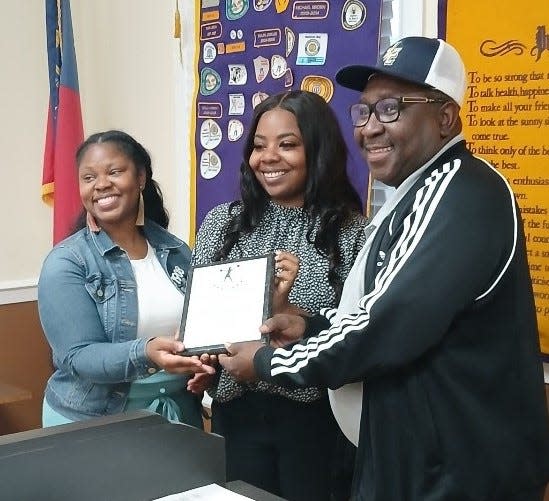 Wrens North Jefferson Optimist President Michael Brown presents Jefferson County Middle School Cheer Coaches Jeannetta Mayle and Hyquel Temple with a plaque recognizing their team's talent and dedication in winning the school's first cheer state championship.
