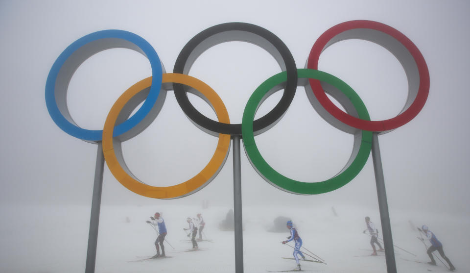 Cross-country skiers train underneath the olympic rings at the Laura biathlon and cross-country ski center, at the 2014 Winter Olympics, Monday, Feb. 17, 2014, in Krasnaya Polyana, Russia. After days of warm weather at the Sochi Olympics, fog up in the mountains is causing an even bigger disturbance. Thick fog rolled in over the mountains in Krasnaya Polyana on Sunday night and was still lingering on Monday, and the limited visibility forced organizers to delay a biathlon race and cancel the seeding runs in a snowboard event. (AP Photo/Gero Breloer)