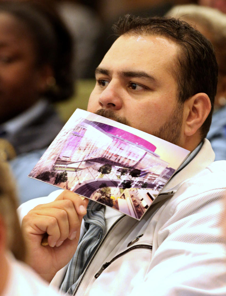 A supporter of a new sports and entertainment center, holding a card with an illustration of the new arena, listens to the discussion of the arena plan by the Sacramento City Council, during a meeting in Sacramento, Calif. Tuesday, March 6, 2012. A year after the NBA's Sacramento Kings almost moved to Anaheim, Sacramento's plan to help finance a new $391 million arena was a vote away from approval Tuesday night. (AP Photo/Rich Pedroncelli)