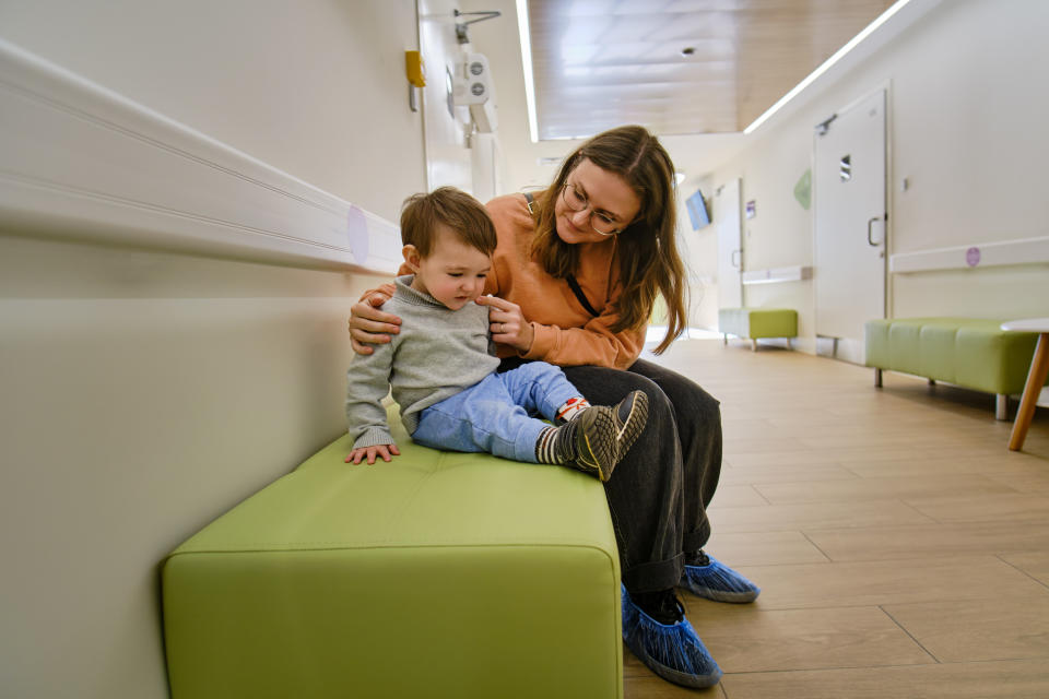 Woman and young child sitting together on a bench indoors, sharing a moment