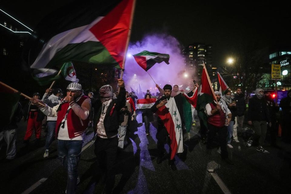 People wave Palestinian flags as smoke bombs are set off during a demonstration in support of Palestine in Vancouver on Thursday, October 19, 2023.