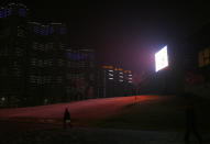 In this Tuesday Feb. 25, 2014 photo, a North Korean man walks near a big screen on a street near a residential complex which is lit at night in Pyongyang, North Korea. (AP Photo/Vincent Yu)