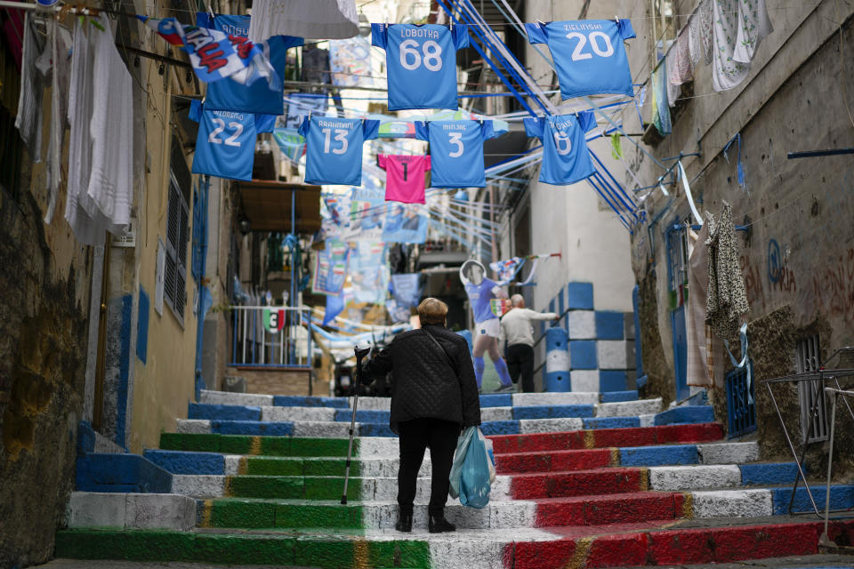 A woman walks among banners and writings in support of Napoli soccer team in downtown Naples, Italy, Tuesday, April 18, 2023. It's a celebration more than 30 years in the making, and historically superstitious Napoli fans are already painting the city blue in anticipation of the team's first Italian league title since the days when Diego Maradona played for the club. (AP Photo/Andrew Medichini)