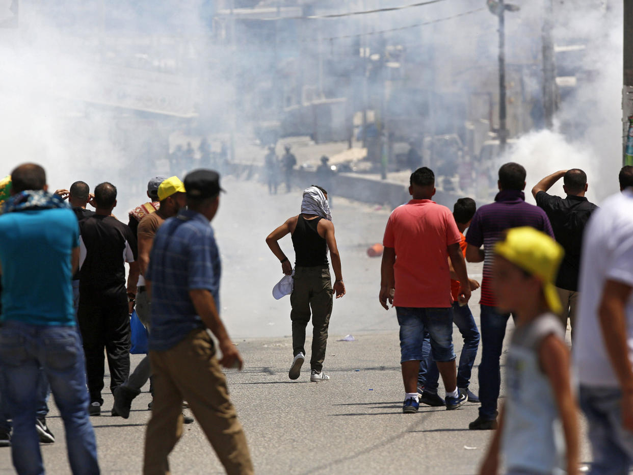 Israeli soldiers fire tear gas at Palestinian protesters during clashes after a protest at Qalandiya checkpoint near the West Bank city of Ramallah on 21 July: EPA