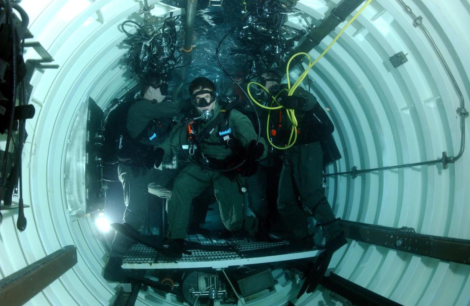 Navy SEALs inside a flooded dry deck shelter mounted on the back of the USS Philidelphia.