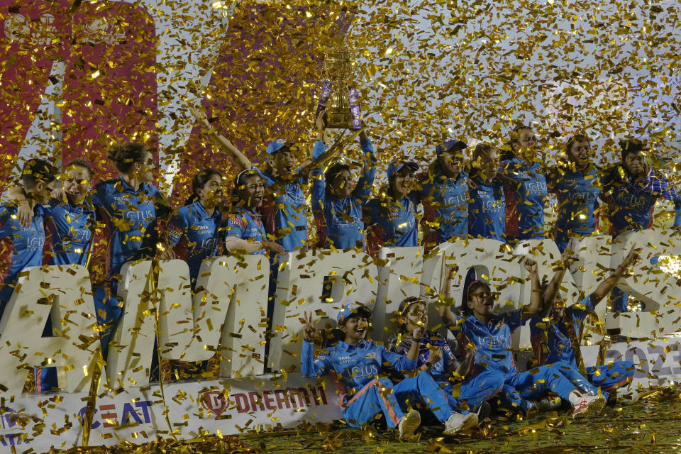 Members of Mumbai Indians team pose with the trophy after their win over Delhi Captials in the Women's Premier League Twenty20 cricket final in Mumbai, India, Sunday, March 26, 2023. (AP Photo/Rajanish Kakade)