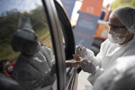 A health worker collects a blood sample at a drive-thru test site for COVID-19 amid the new coronavirus pandemic in Niteroi, Brazil, Wednesday, June 3, 2020. (AP Photo/Silvia Izquierdo)