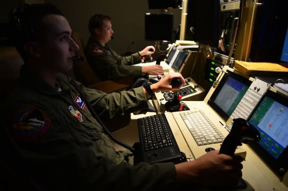 Two drone operators remotely fly an MQ-1 Predator aircraft on Oct. 22, 2013.