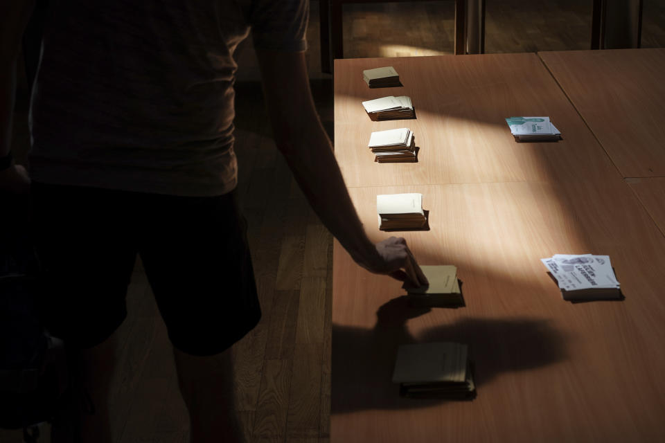 A voter picks up ballots before voting in the second round of the French parliamentary election in Lyon, central France, Sunday, June 19, 2022. French voters are going to the polls in the final round of key parliamentary elections that will demonstrate how much legroom President Emmanuel Macron's party will be given to implement his ambitious domestic agenda. (AP Photo/Laurent Cipriani)