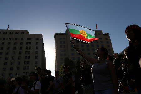 A Mapuche indigenous activist waves a flag outside government house during a protest demanding justice for Camilo Catrillanca, an indigenous Mapuche man who was shot in the head during a police operation, in Santiago, December 20, 2018. REUTERS/Ivan Alvarado