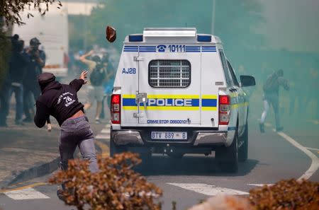 A student throws a rock at a South African police car during clashes over high tuition fees at Johannesburg's University of the Witwatersrand, South Africa. REUTERS/Siphiwe Sibeko