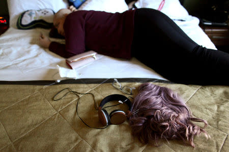 Keyshla Betancourt, 22, lies on a bed after her first radiotherapy treatment, at a hotel where she lives in Orlando, Florida, U.S., December 11, 2017. REUTERS/Alvin Baez