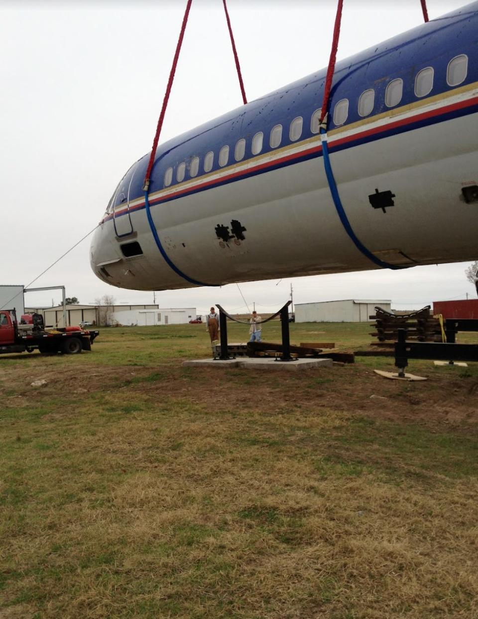 McDonnell Douglas MD-80 being lowered on to steel support beams and foundations.