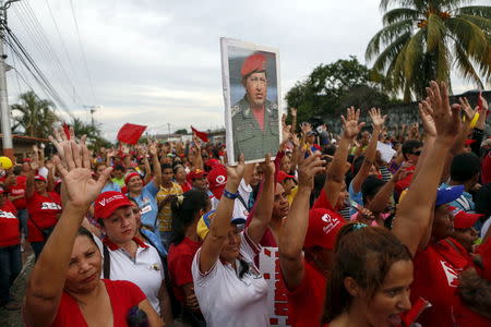 A supporter of late Venezuela's President Hugo Chavez holds a poster of him during a campaign rally held by pro-government candidates for the upcoming legislative elections, in Barinas, November 18, 2015. REUTERS/Marco Bello.