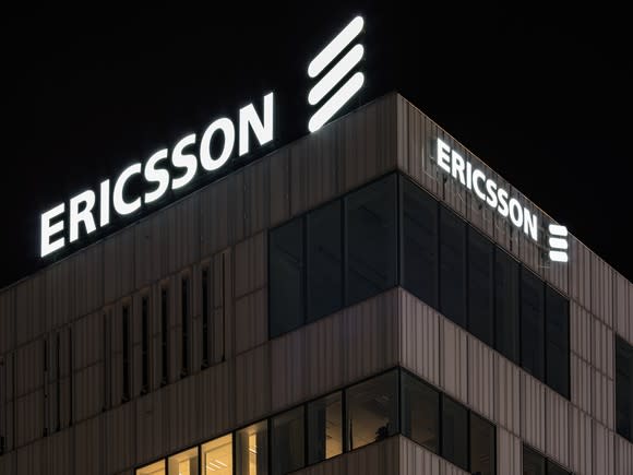 LM Ericsson's corporate logo atop the Stockholm HQ building, bright white against a black sky.