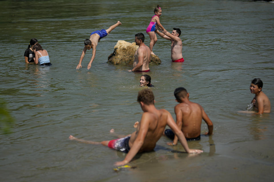People cool off in the river Arges, outside Bucharest, Romania, Wednesday, July 12, 2023. Weather services issued a heat warning for the coming days in southern Romania, with temperatures expected to exceed 40 degrees Centigrade (104 Fahrenheit) in the shade. (AP Photo/Andreea Alexandru)