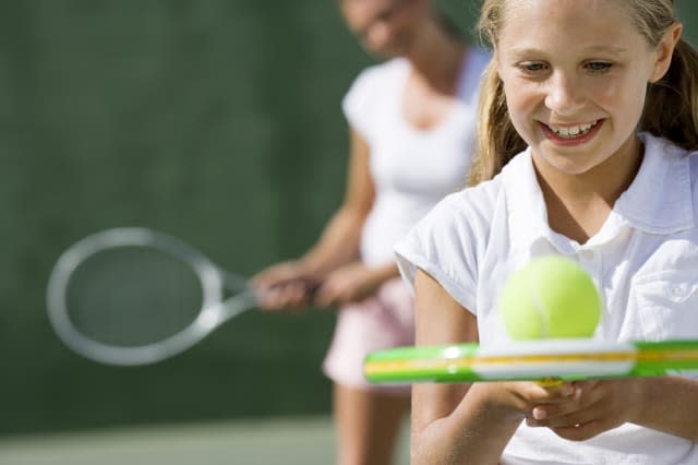 Girl balancing ball on tennis racket