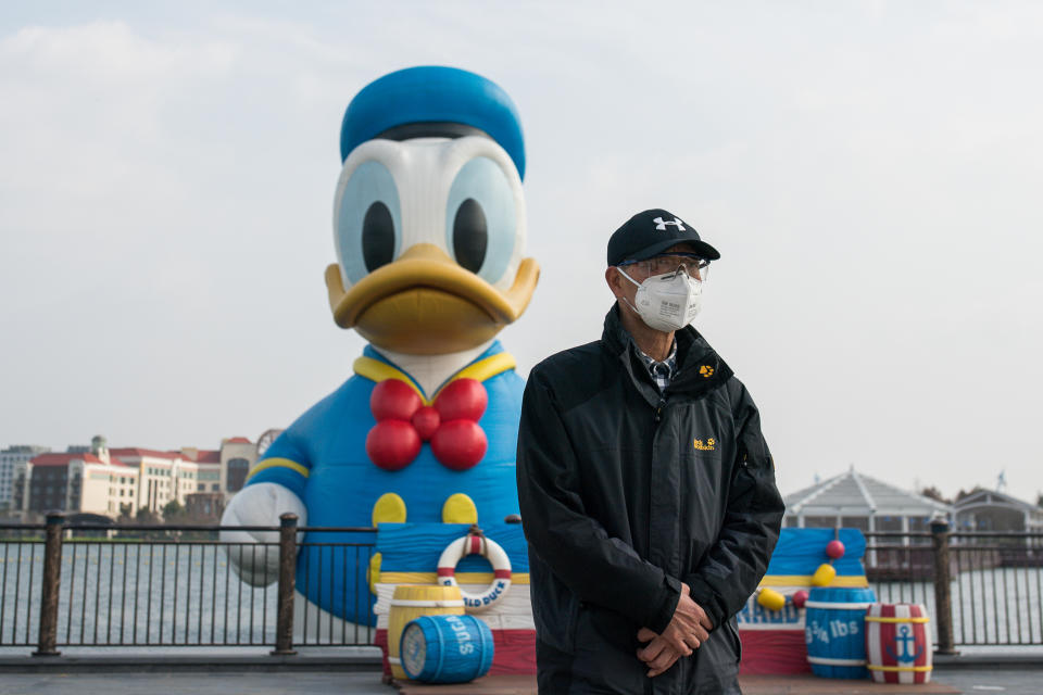 SHANGHAI, CHINA - MARCH 10: A tourist wearing a protective mask and protective glasses walks by a floating sculptures of Donald Duck in Shanghai Disneyland Park on March 10, 2020 in Shanghai, China. The Shanghai Disney Resort has said it will reopen some of the shopping, dining and entertainment options on Monday, though the main theme park will remain closed to prevent further spread of the coronavirus. Twenty-one of mainland China's 31 regions have lowered emergency response levels on the flu-like epidemic by March 1, allowing greater movement of people and goods and a recovery in business activity. Since the outbreak began in December last year, more than 80,000 cases have been confirmed in China, with the death toll rising to more than 3,100. As of today, the number of cases of new coronavirus COVID-19 being treated in China dropped to approximately 17,800 in China. The World Health Organization (WHO) declared to raises coronavirus threat assessment to “very high” globally by the end of February. (Photo by Yifan Ding/Getty Images)