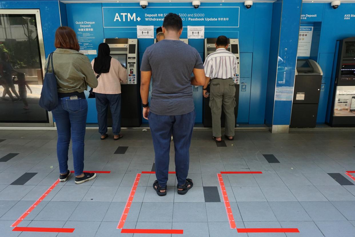 People wait to use ATM machines while standing in areas demarcated for social distancing, as a preventive measure against the spread of the COVID-19 novel coronavirus, at Tanjong Pagar Plaza in Singapore on April 1, 2020. (Photo by Roslan RAHMAN / AFP) (Photo by ROSLAN RAHMAN/AFP via Getty Images)