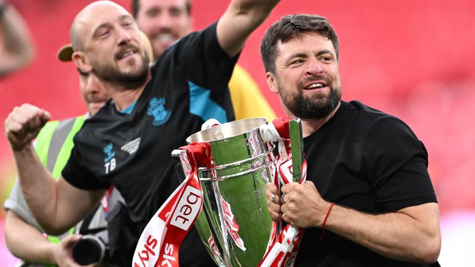 Russell Martin holds the play-off trophy in both hands as he prepares to lift iti t