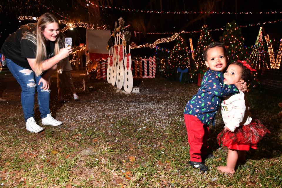 A'Lea Smith, takes a photo of her kids, Jet, 2, and Josie, 1,  while visiting a Christmas display, complete with falling "snow", at a home in Sarasota. 