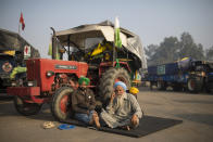 Protesting farmers, Raghuvir Singh, right, and Gurnam Singh bask in the morning sun while sitting next to their tractor parked on a highway, during a protest at the Delhi-Haryana state border, India, Tuesday, Dec. 1, 2020. Instead of cars, the normally busy highway that connects most northern Indian towns to the capital is filled with tens of thousands of protesting farmers, many wearing colorful turbans. Their convoy of trucks, trailers and tractors stretches for at least three kilometers (1.8 miles). Inside, they have hunkered down, supplied with enough food and fuel to last weeks. (AP Photo/Altaf Qadri)