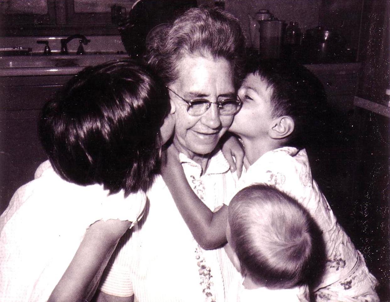 Annie Thompson McKinney — on her 64th birthday in 1967 — receives kisses from her grandchildren, Laura McKinney Wilfong (now Holland), left; Harry Wilfong, right; and Billy Wilfong in front.