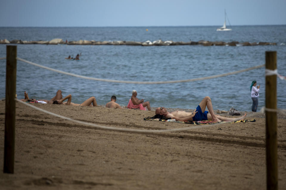 Tourists sunbathe in a beach in Barcelona, Spain, Thursday, July 16, 2020. With Europe's summer vacation season kicking into high gear for millions weary of months of lockdown, scenes of drunken British and German tourists on Spain's Mallorca island ignoring social distancing rules and reports of American visitors flouting quarantine measures in Ireland are raising fears of a resurgence of infections in countries that have battled for months to flatten the COVID-19 curve. (AP Photo/Emilio Morenatti)