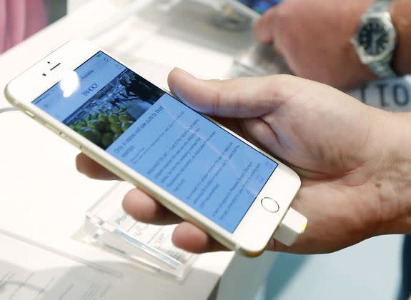 A customer looks at the screen size on an iPhone 6 Plus while waiting in line to upgrade his iPhone at a Verizon Wireless store in Flowood, Miss.