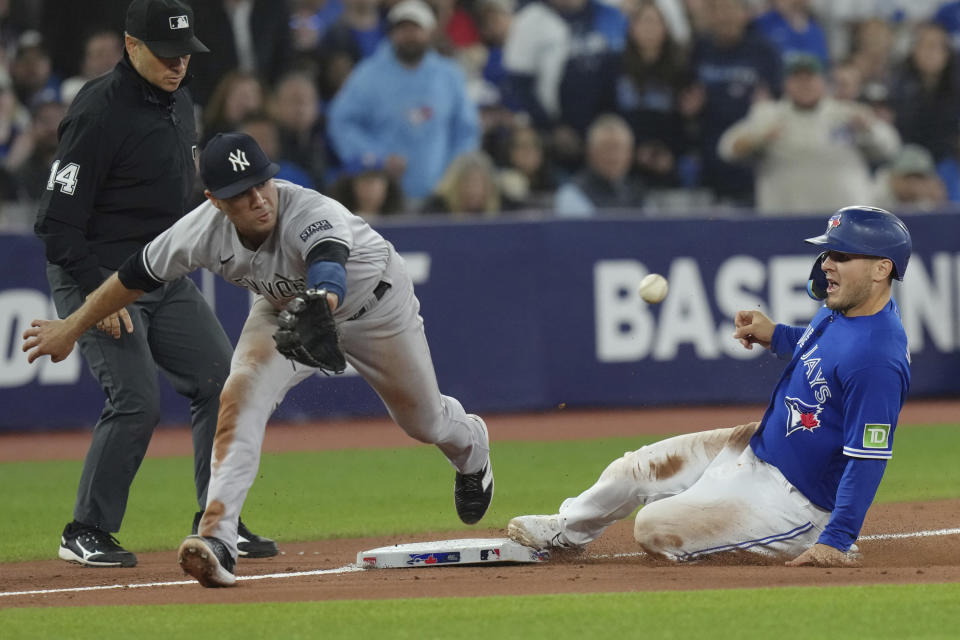 Toronto Blue Jays' Daulton Varsho, right, steals third base in front of New York Yankees' Isiah Kiner-Falefa during the seventh inning of a baseball game in Toronto on Tuesday, Sept. 26, 2023. (Chris Young/The Canadian Press via AP)