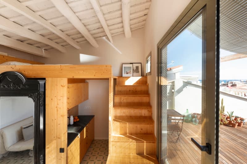 small white apartment with wood stairs leading up to loft space