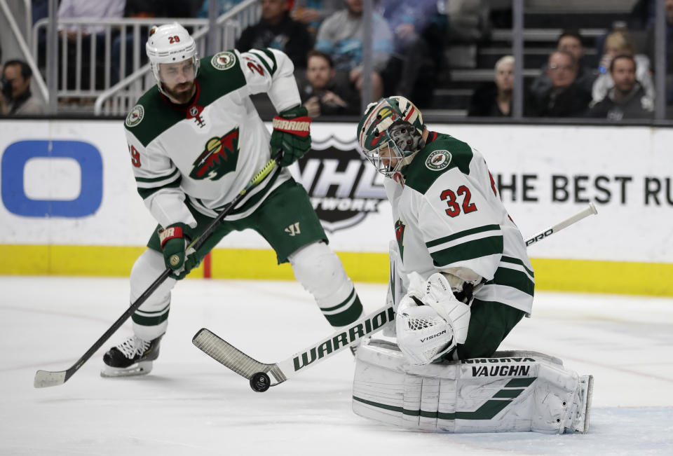 Minnesota Wild goalie Alex Stalock, right, blocks a shot from the San Jose Sharks in the first period of an NHL hockey game Thursday, March 5, 2020, in San Jose, Calif. At left is Wild defenseman Greg Pateryn (AP Photo/Ben Margot)