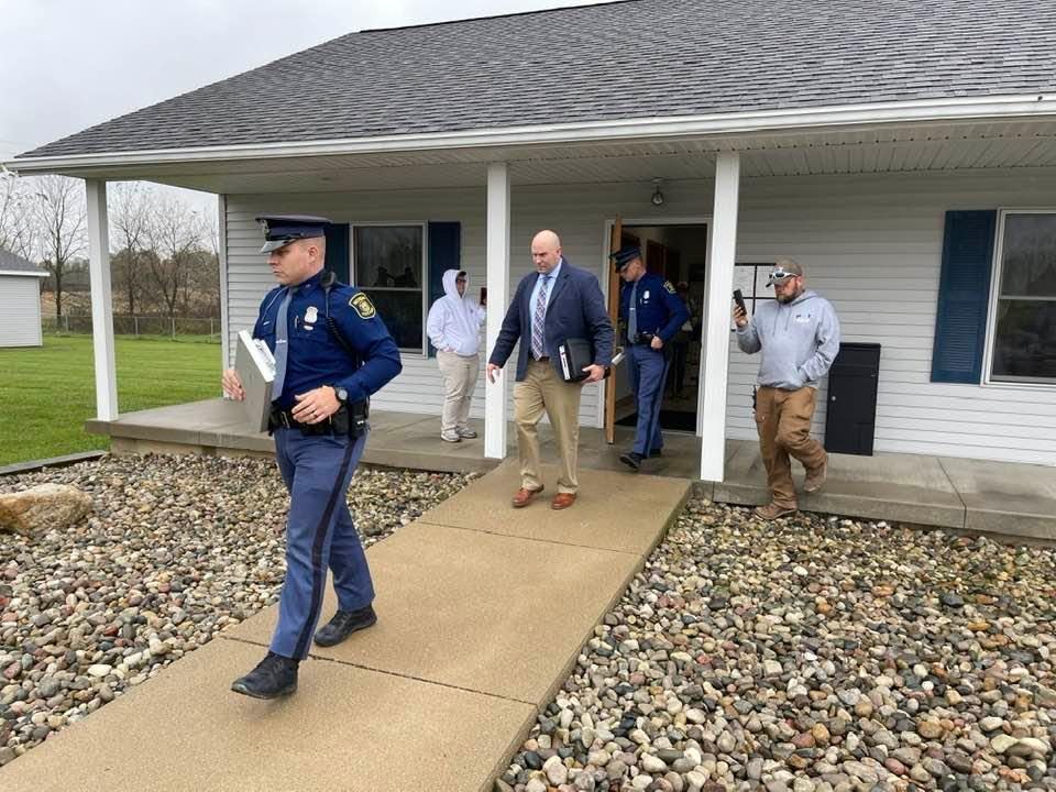 Michigan State Police Troopers exit the Adams Township Hall with a tablet-device seized during the execution of a search warrant on Oct. 29, 2021.