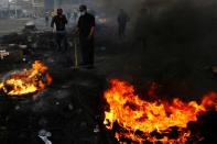 Iraqi demonstrators burn tires to block a street during ongoing anti-government protests in Najaf