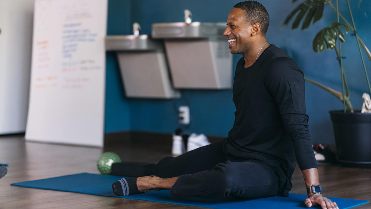  Man doing hip stretches in a yoga class. 