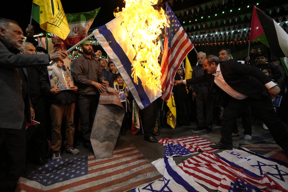 Iranian protesters burn representations of the U.S. and Israeli flags during their gathering to condemn killing members of the Iranian Revolutionary Guards in Syria, at the Felestin (Palestine) Sq. in downtown Tehran, Iran, Monday, April 1, 2024. An Israeli airstrike that demolished Iran's consulate in Syria killed two Iranian generals and five officers, Syrian and Iranian officials said Monday. (AP Photo/Vahid Salemi)