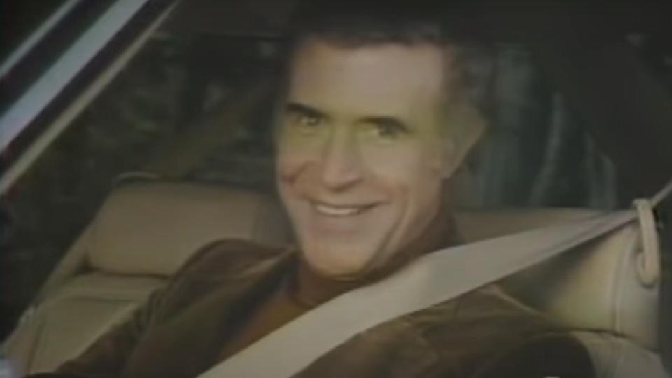 Ricardo Montalban sits smiling behind the wheel for Chrysler