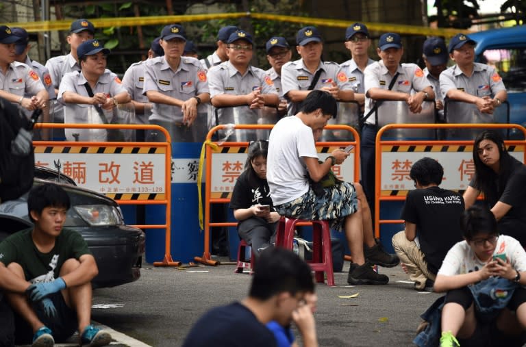 Policemen stand guard as protesters gather on a road near an entrance of the Education Ministry in Taipei on July 31, 2015