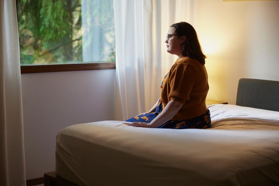 Woman sitting in a room looking out the window.