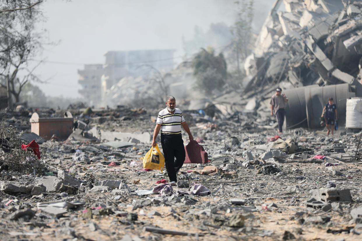 Palestinians walk by buildings destroyed in the Israeli bombardment on al-Zahra, on the outskirts of Gaza City (AP)