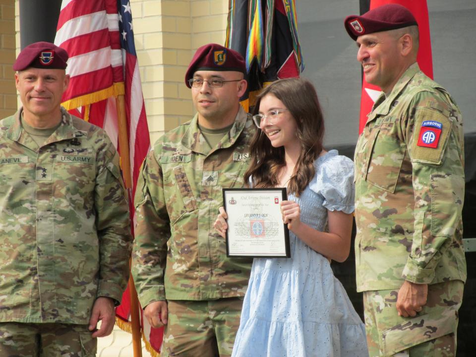 Savanna Oen is joined by her father, Sgt. Stephen Oen, while she is recognized by Maj. Gen. Christopher LaNeve, far left, and Command Sgt. Maj. Randolph Delapena, far right, during a Junior Paratrooper of the Year ceremony Tuesday, May 23, 2023, at Fort Bragg.