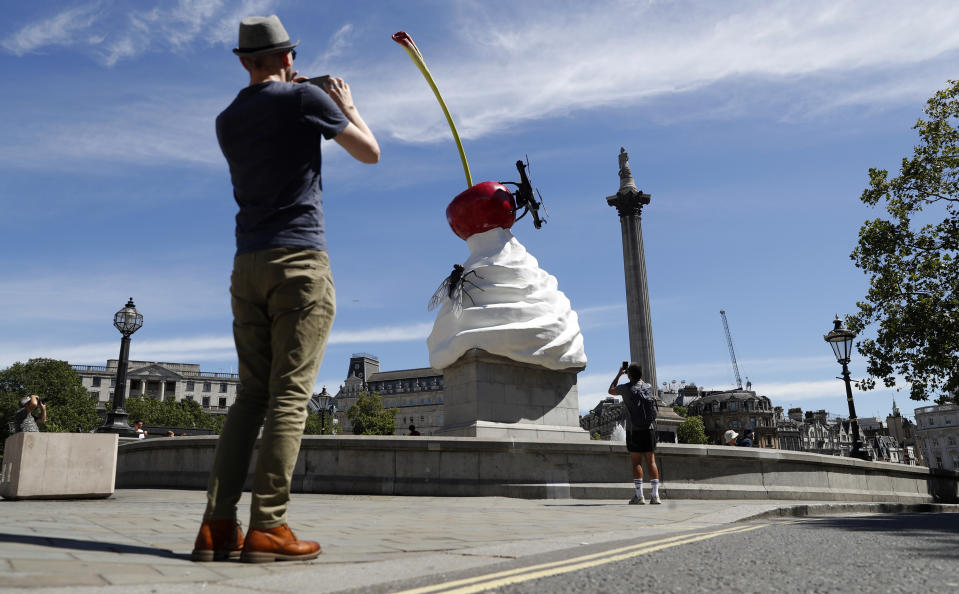 A man takes a smart phone picture of the new work of art entitled 'The End' by artist Heather Phillipson which was unveiled on the fourth plinth in Trafalgar Square in London, Thursday, July 30, 2020. Described as representing "exuberance and unease" and a "monument to hubris and impending collapse", The End, by British artist Heather Phillipson, will stay in place until spring 2022. (AP Photo/Alastair Grant)