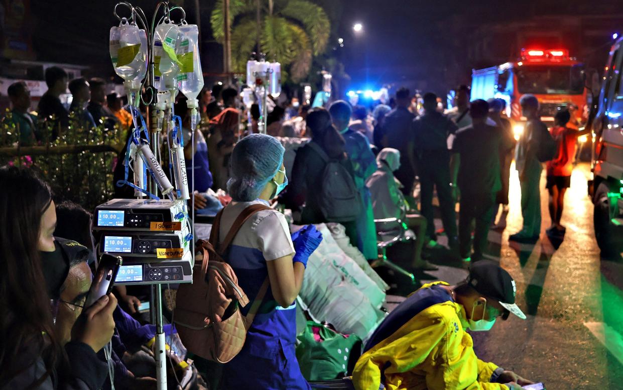 Residents and medical personnel evacuate patients from inside a hospital after a 7.6 earthquake struck Butuan City on the southern island of Mindanao