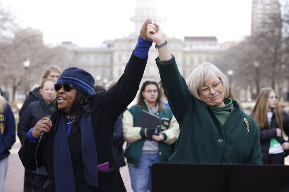 FILE - Michigan Rep. Brenda Carter, D-Pontiac, left, and Sen. Rosemary Bayer, D-Keego Harbor, join hands during a news conference to call for gun reform, Feb. 20, 2023, in Lansing, Mich. New gun laws take effect Tuesday, Feb. 13, 2024, in Michigan on the one-year anniversary of a shooting at Michigan State University that claimed the lives of three students and left five in critical condition. (AP Photo/Al Goldis, File)