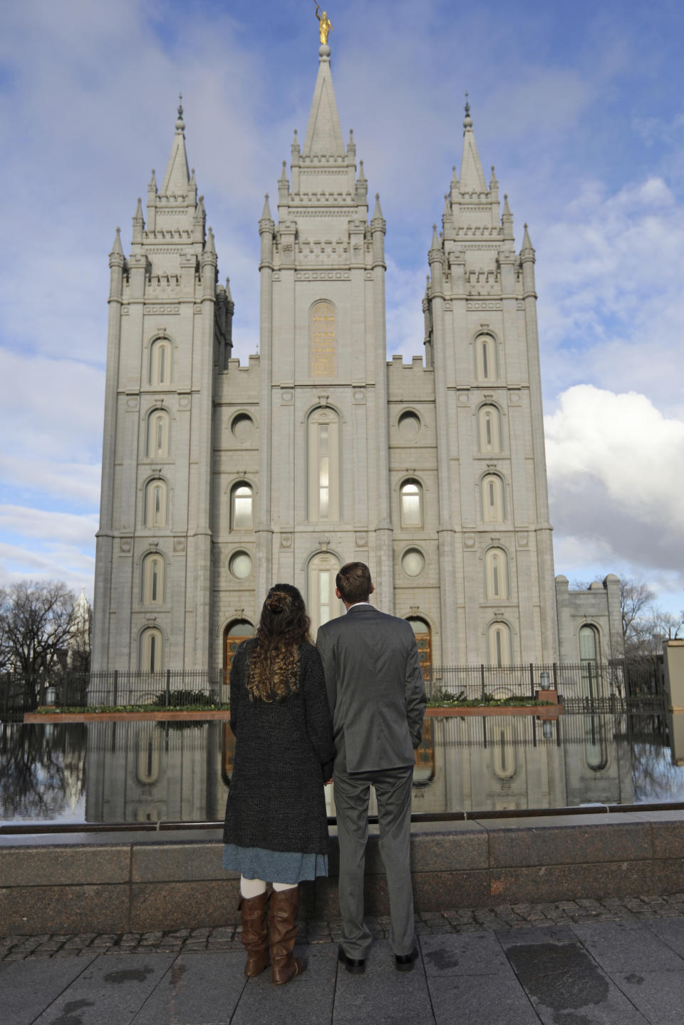 FILE - In this April 6, 2019, file photo, a couple looks at the Salt Lake City temple during the The Church of Jesus Christ of Latter-day Saints' two-day conference. The Church of Jesus Christ of Latter-day Saints added new language to the faith's handbook Friday, Dec. 18, 2020. imploring members to root out prejudice and racism, adding significance and permanence to recent comments by top leaders on one of the most sensitive topics in the church's history. (AP Photo/Rick Bowmer, File)