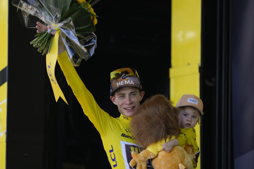 Denmark's Jonas Vingegaard, wearing the overall leader's yellow jersey, hold his daughter Frida as he celebrates on the podium after the twentieth stage of the Tour de France cycling race, an individual time trial over 40.7 kilometers (25.3 miles) with start in Lacapelle-Marival and finish in Rocamadour, France, Saturday, July 23, 2022. (AP Photo/Thibault Camus)